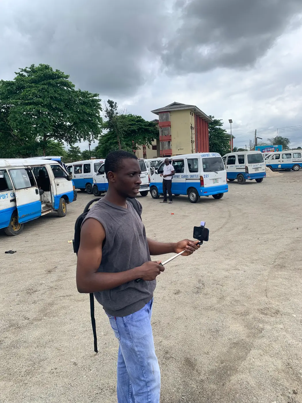 odii filming the motor park with the phone held out in front of him